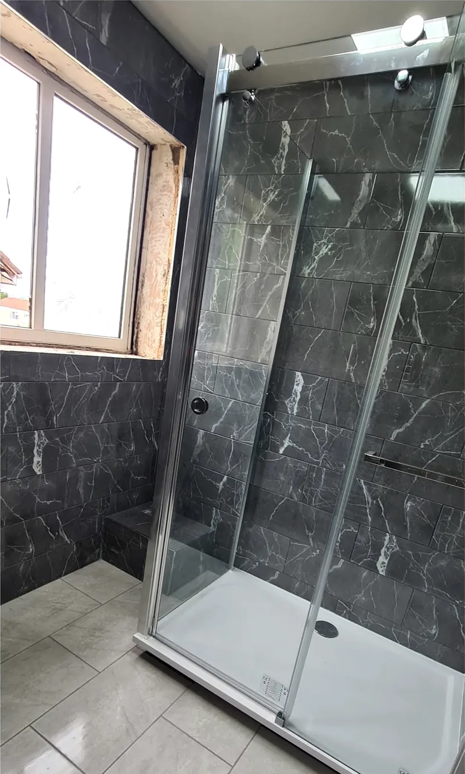After: glass shower enclosure and dark marble-effect walls