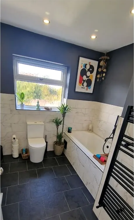 Finished bathroom with dark floor tiles and white bath